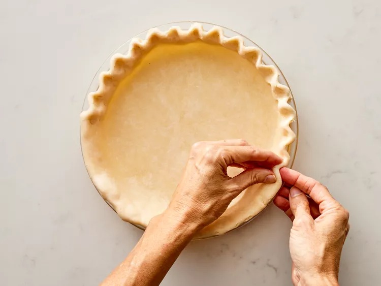 I roll the dough around the rolling pin and carefully lay it into the pie pan. I ease it into the corners, trim if needed, and crimp the edges using my fingers and whatever confidence I have that day.