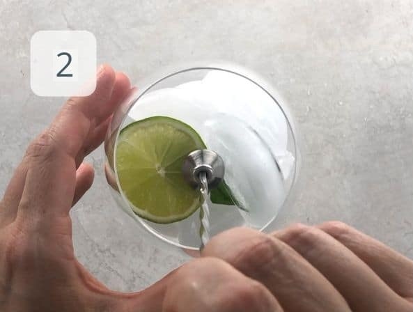 Add one lime wheel and a few mint leaves to the glass. Gently muddle them to release their aroma