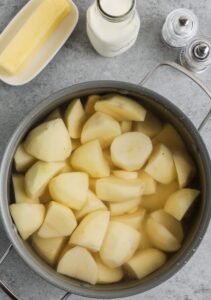 I start by peeling the potatoes and cutting them into quarters. Nothing fancy. I toss them into a big pot and cover them with cold water, then add a good pinch of salt. If I’m using garlic, I throw the cloves in now and hope for the best.