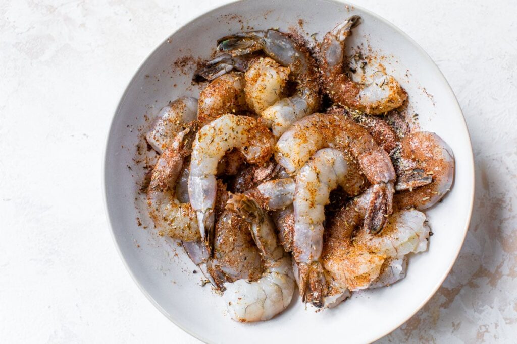 In a bowl, mix olive oil with all the spices, then gently toss the shrimp until evenly coated