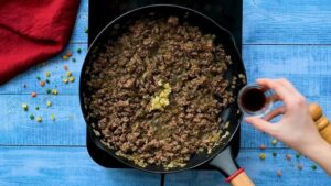 Next comes the ground beef. I break it up with a wooden spoon and add the dried herbs, salt, and pepper. I let it cook until browned, usually six to eight minutes. Then I add the Worcestershire sauce and garlic and cook it for one more minute, just until it smells amazing.
