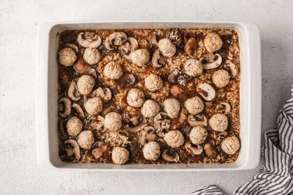 Remove the foil and arrange the frozen meatballs evenly over the rice. Do not thaw them first.