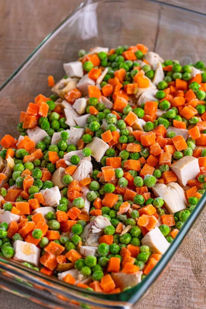 Sprinkle the frozen peas and carrots evenly over the chicken layer. Again, do not stir