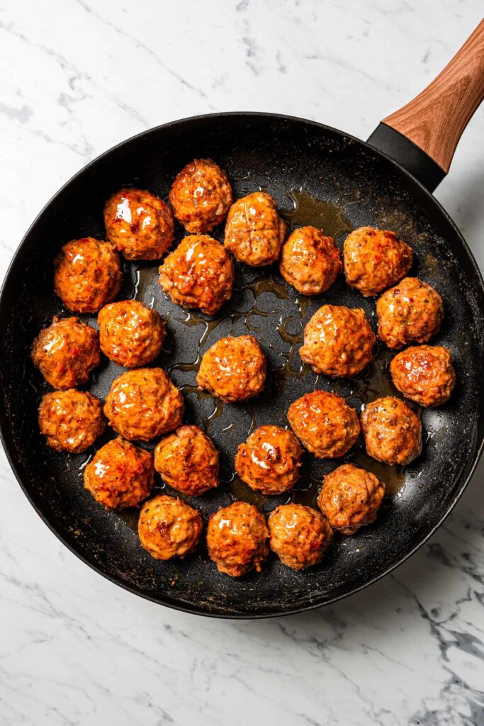 Add the baked meatballs to the pan and cook over medium heat, turning once, until coated and glossy