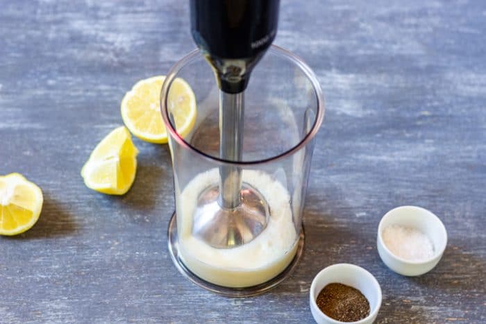 Add the egg, crushed garlic, and about a quarter cup of olive oil to a tall blending beaker