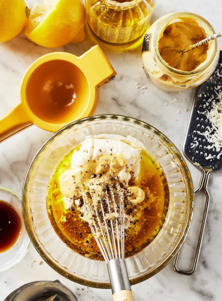 In a large measuring cup or bowl, whisk together the mayonnaise, olive oil, lemon juice, Dijon mustard, grated garlic, Worcestershire sauce, salt, and pepper until smooth