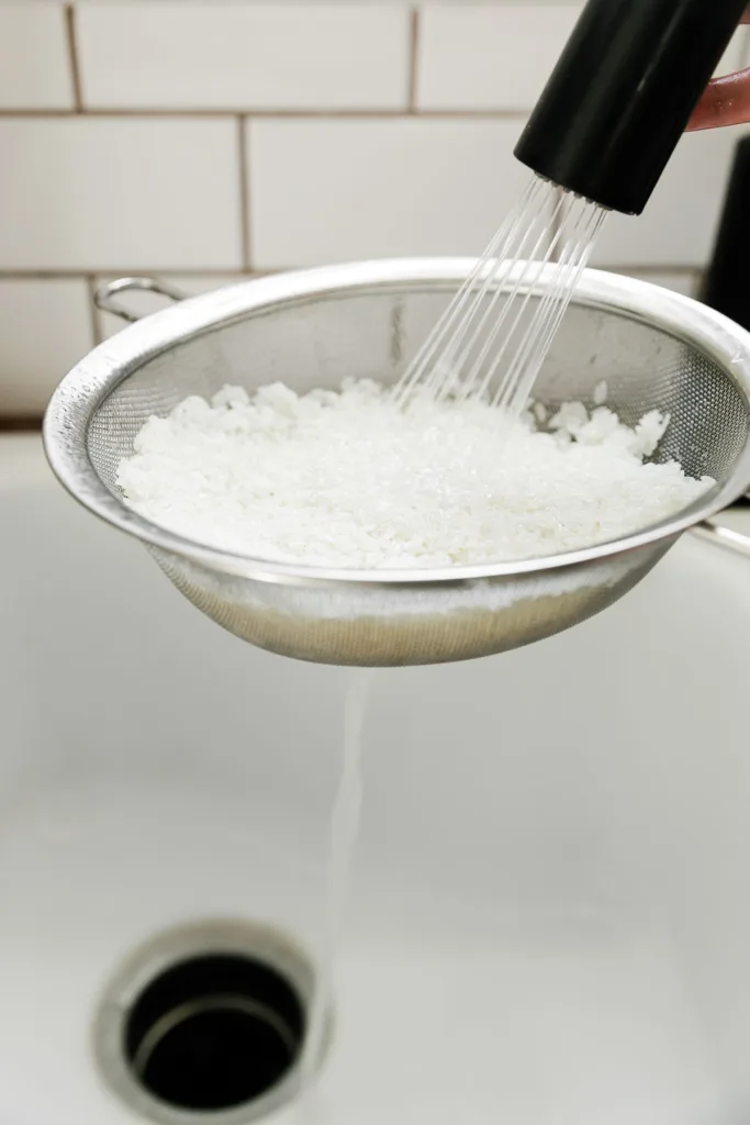 Cook the rice by rinsing it in a fine mesh colander under hot water until the water runs clear