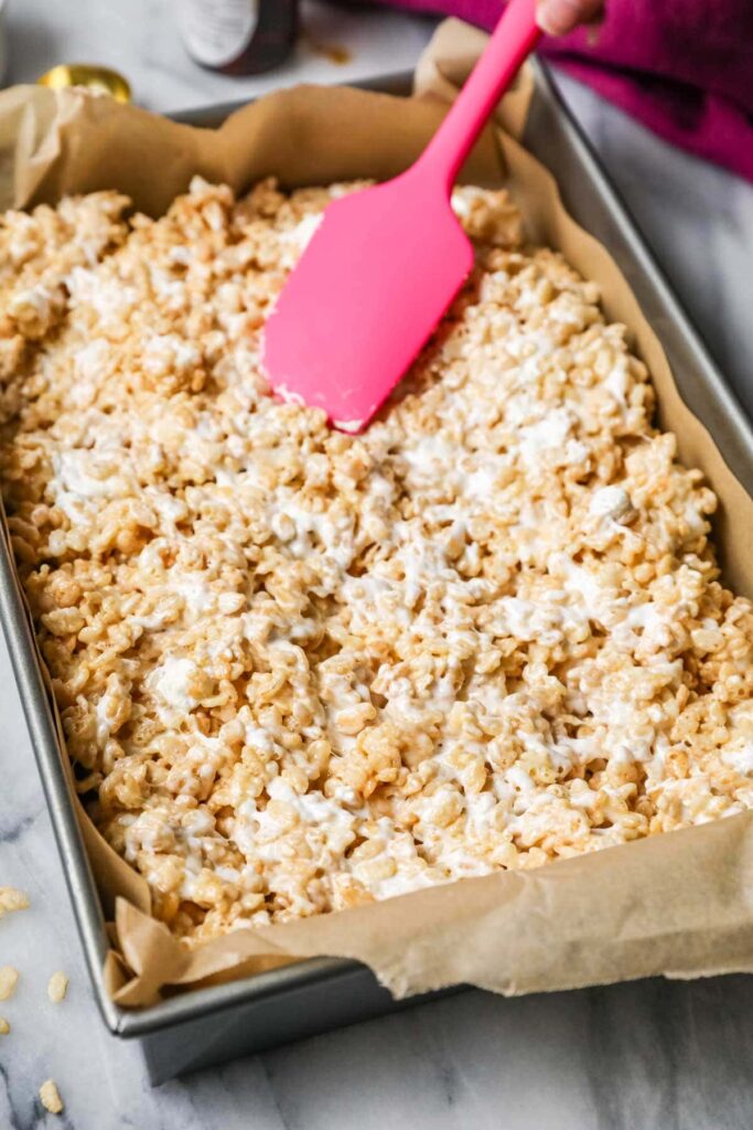 Immediately transfer the mixture into the prepared pan. Using a silicone spatula or lightly greased hands, gently press the mixture evenly into the pan without packing it down too firmly