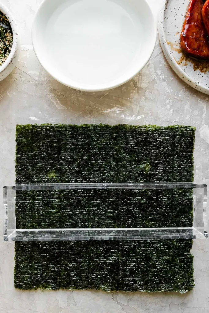 Place a sheet of nori shiny-side down on plastic wrap