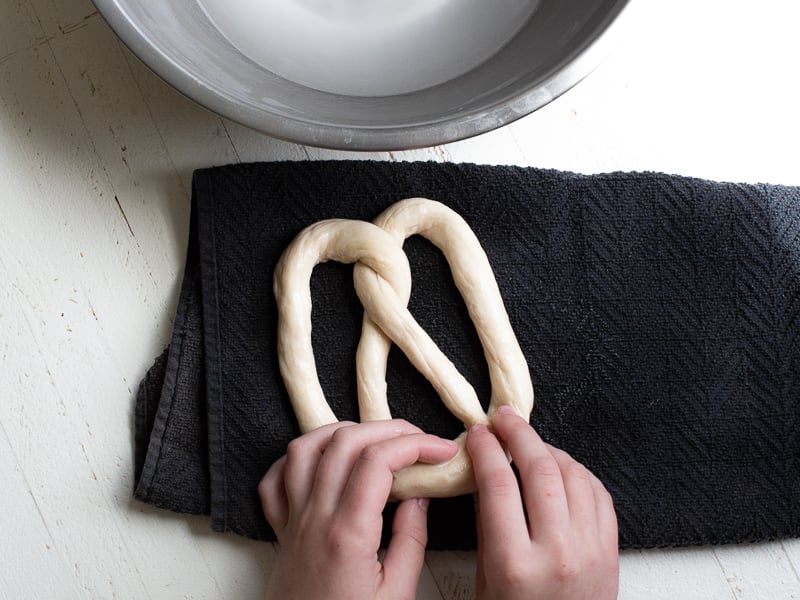 Roll each piece into a 35–40 inch rope about finger thickness. Form into a U-shape, twist twice, and press ends down to create the classic pretzel shape
