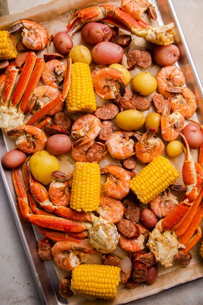 Using a strainer, carefully remove the seafood, sausage, potatoes, and corn from the pot and place them on the tray