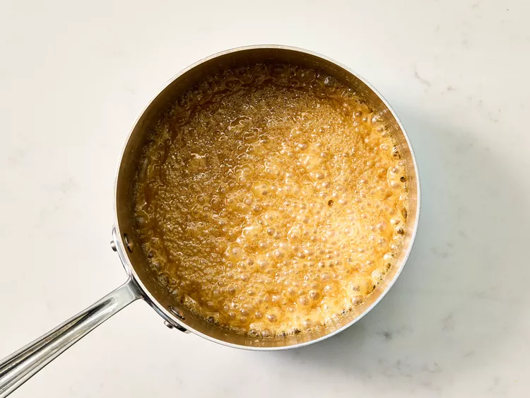 Add both sugars and water, bringing the mixture to a boil before reducing the heat and allowing it to simmer until slightly thickened.