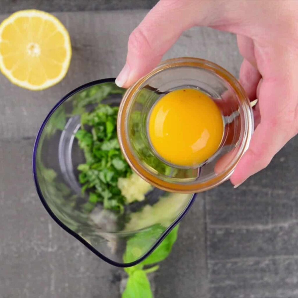 Add the basil, minced garlic, egg yolks, lemon juice, and salt to a food processor