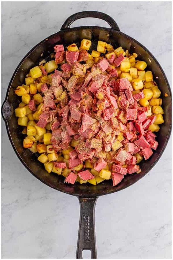Add the chopped corned beef along with the garlic powder and onion powder, stirring gently to distribute everything evenly throughout the pan