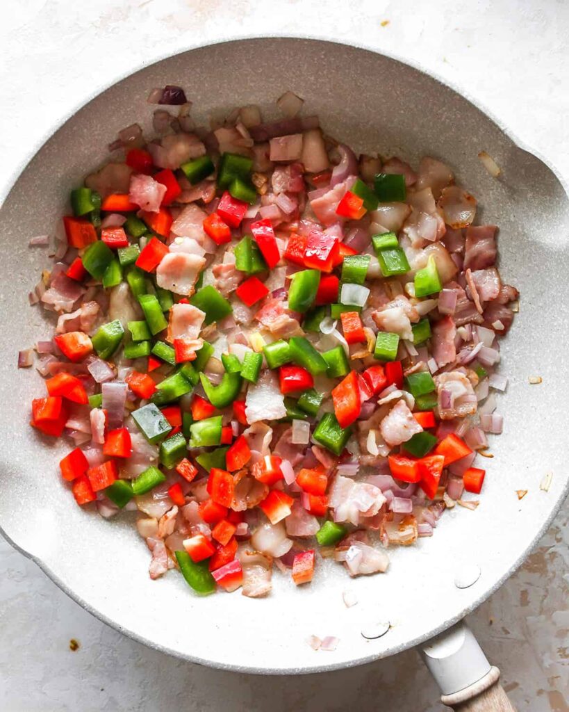 Add the diced vegetables to the skillet, cover, and cook until they are softened and the bacon is fully cooked