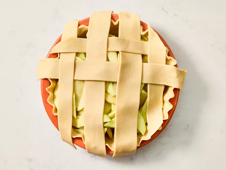 Arrange the strips over the apples in a lattice pattern, weaving them carefully and trimming any excess dough at the edges