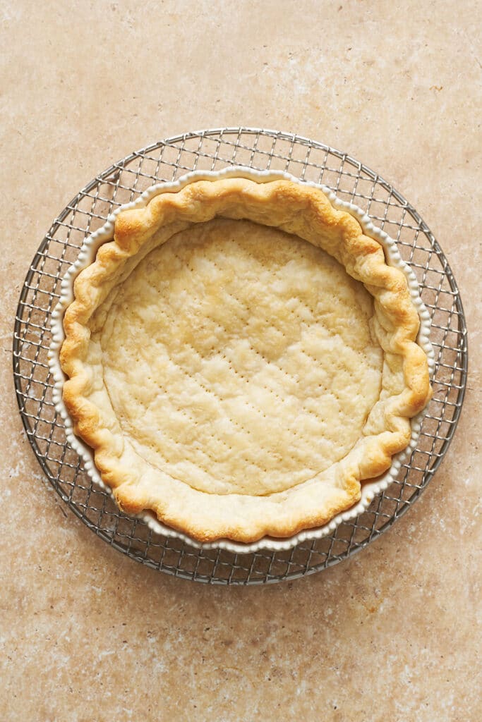 Bake until the edges are set, then remove the weights, prick the base, and continue baking until lightly golden. Reduce the oven temperature afterward