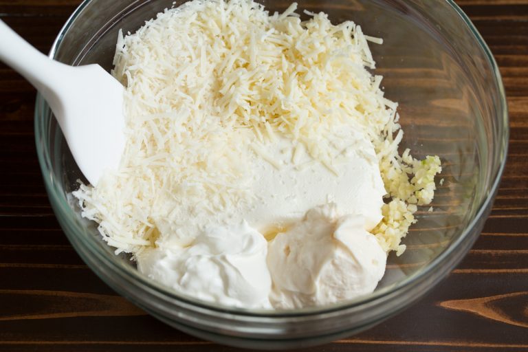 Combine the softened cream cheese, sour cream, mayonnaise, garlic, Parmesan, mozzarella, and pepper in a bowl, stirring until smooth and well blended
