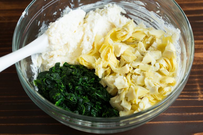 Fold in the chopped artichokes and drained spinach, making sure they are evenly distributed throughout the mixture