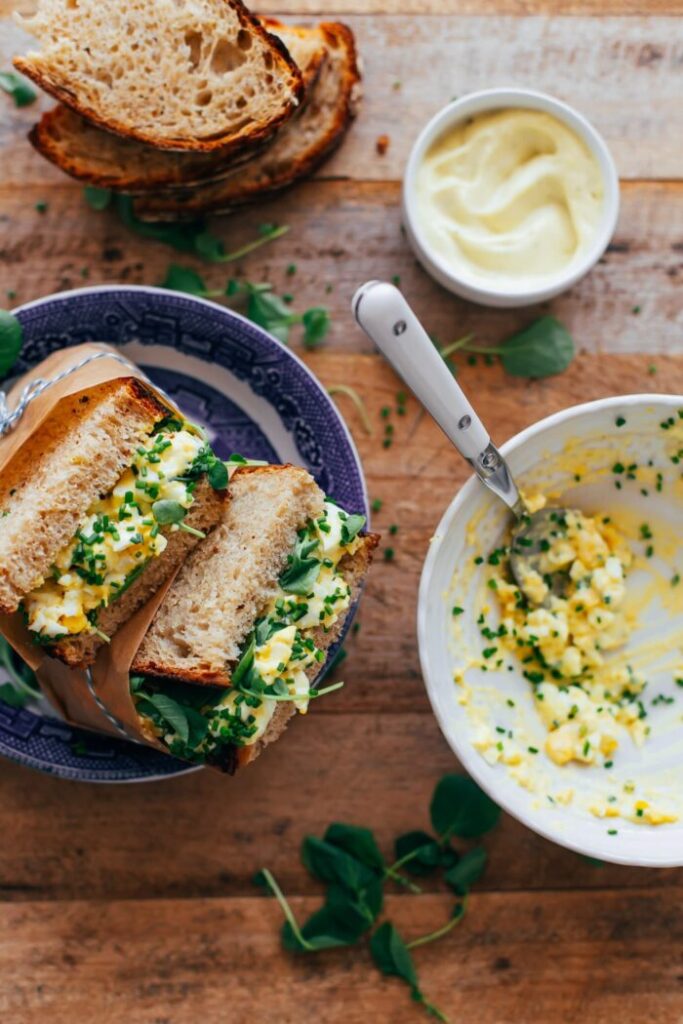 Layer watercress on slices of bread, add a generous portion of egg salad, and top with additional greens and another slice of bread
