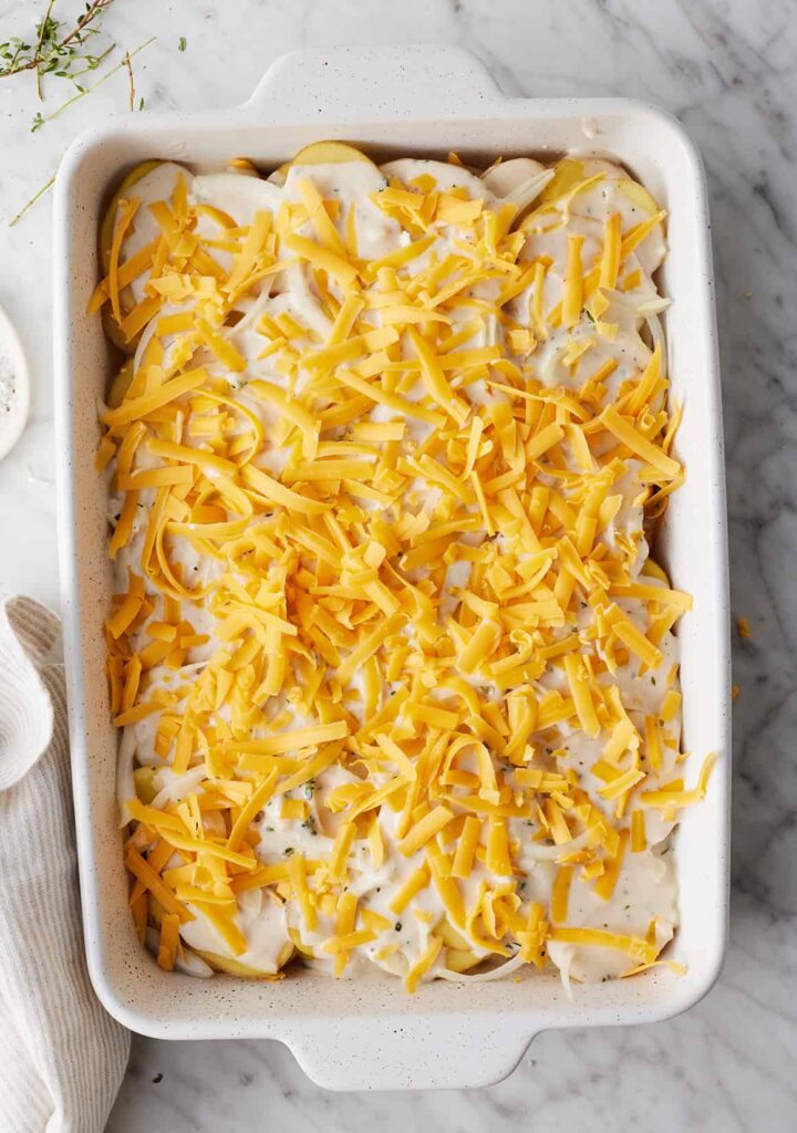 Repeat the layering process with the remaining potatoes, onions, sauce, and cheese