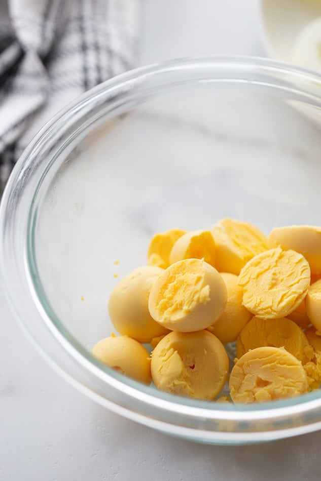 Slice the eggs in half lengthwise and carefully remove the yolks into a bowl, arranging the whites on a serving platter