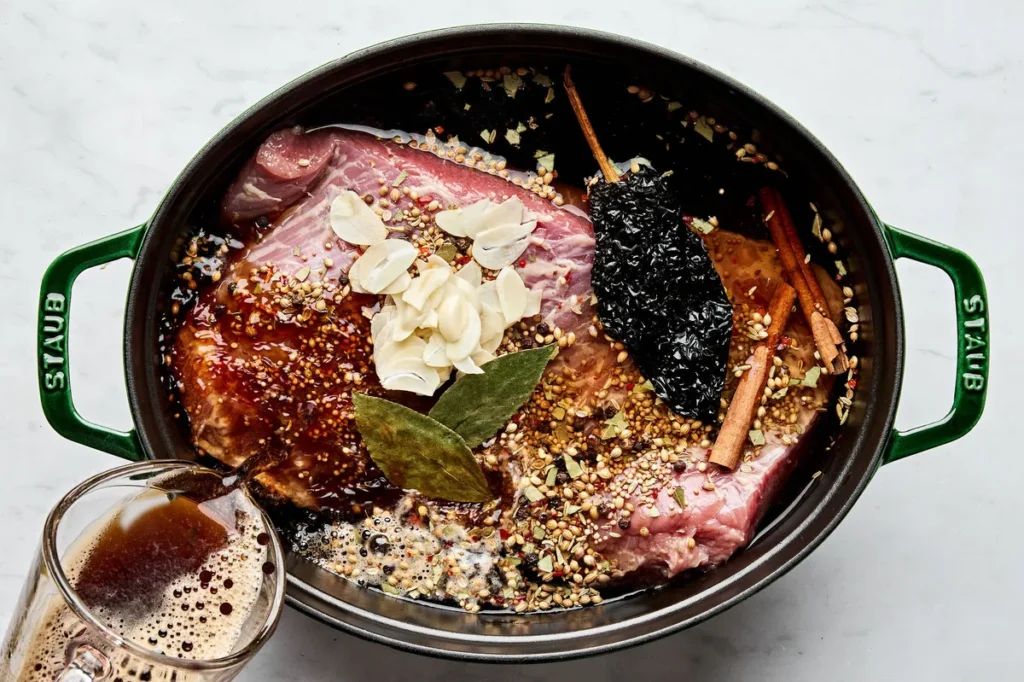 Place the corned beef brisket into a large Dutch oven along with the seasoning packet. Pour in the stout beer and add enough water to just cover the beef. Add cinnamon sticks, garlic, bay leaves, and dried chili if using.