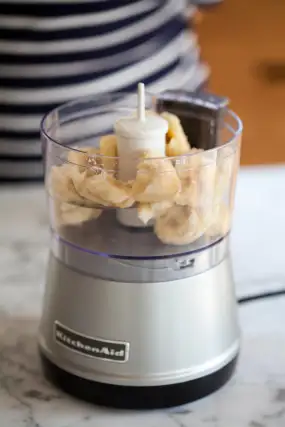 Transfer the frozen banana pieces into a small food processor or high-speed blender. Pulse a few times to break the pieces apart