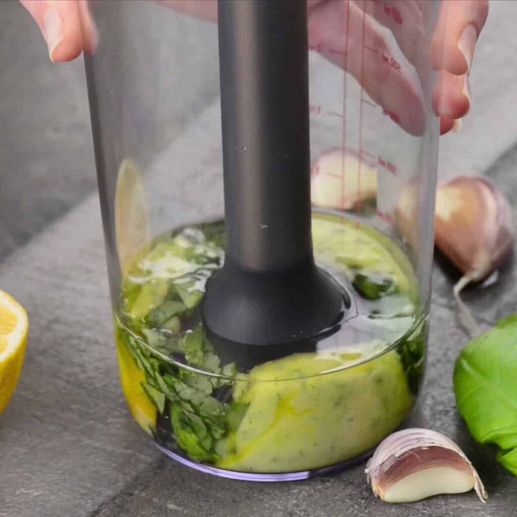 Turn the processor on and slowly drizzle in the olive oil and vegetable oil mixture. Pouring slowly is important for creating a smooth emulsion