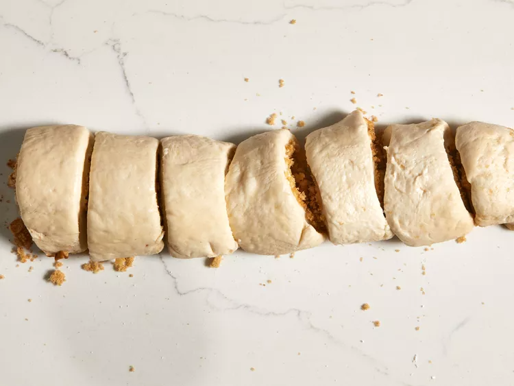 Slice the log into even pieces and place them cut-side down into the prepared pans. Cover with a clean towel and allow the rolls to rise in a warm place until they double in size. Once risen, pour the heavy cream evenly over the rolls.