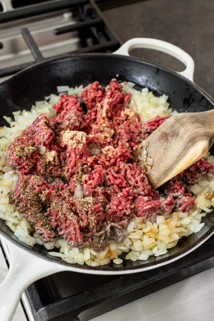 Add the ground beef along with seasoning, breaking it into small pieces as it cooks until browned and fully cooked through