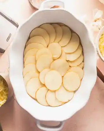 Arrange a layer of thinly sliced potatoes in a baking dish, then spoon some of the cheese sauce over the top and sprinkle with a portion of the remaining cheese
