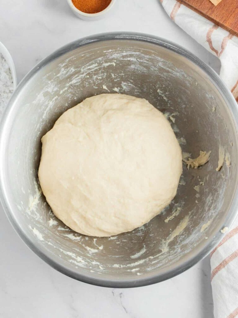 Add flour and salt to a mixing bowl, then pour in the yeast mixture. Knead until a smooth, slightly sticky dough forms. Adjust with small amounts of flour if needed.