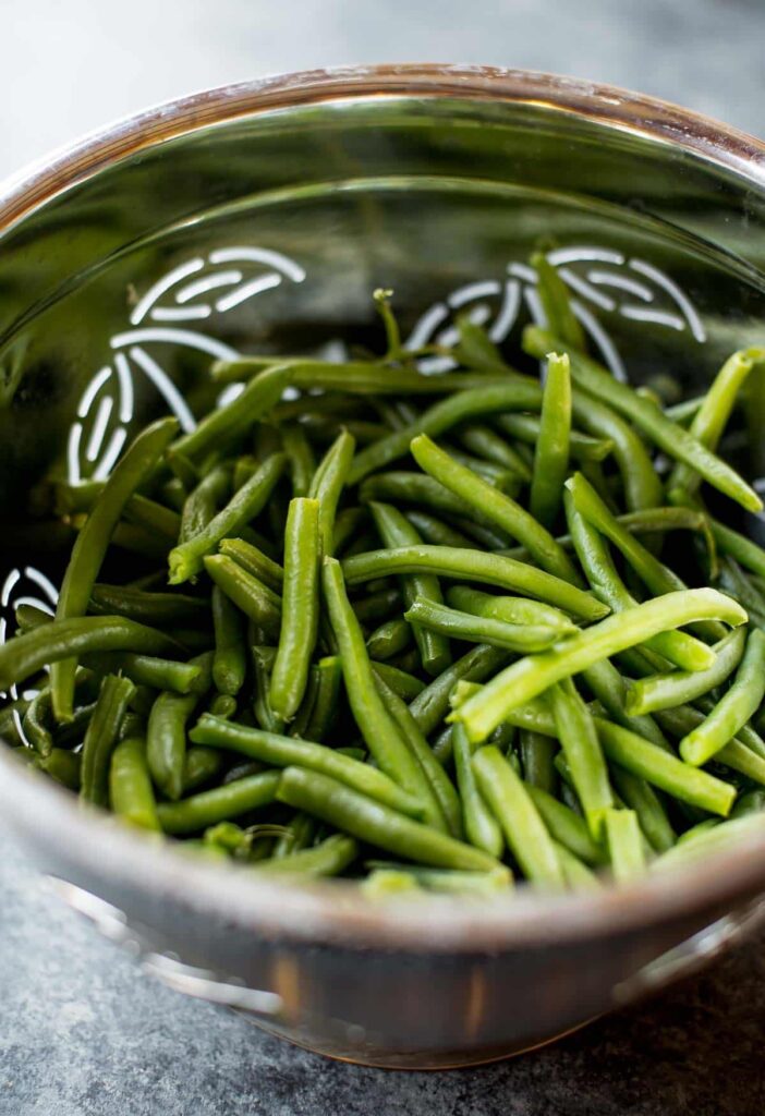 Bring a large pot of salted water to a boil and cook the green beans briefly until just tender. Immediately transfer them to ice water to stop the cooking process, then drain and set aside