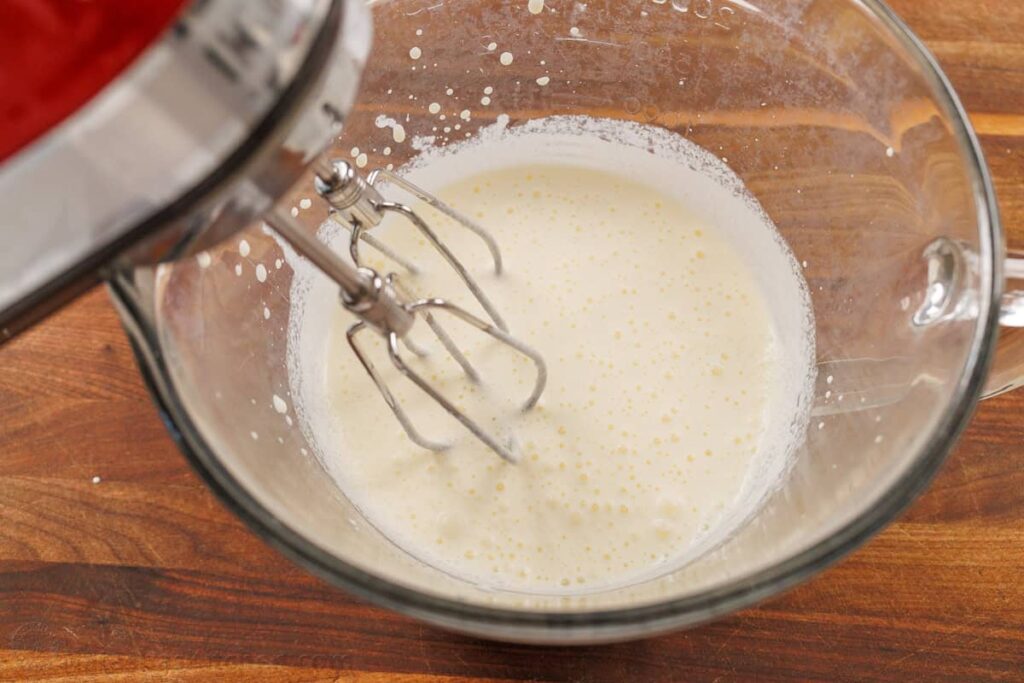 Begin beating the mixture at medium speed until it starts to thicken slightly, then increase to medium-high speed to continue whipping.