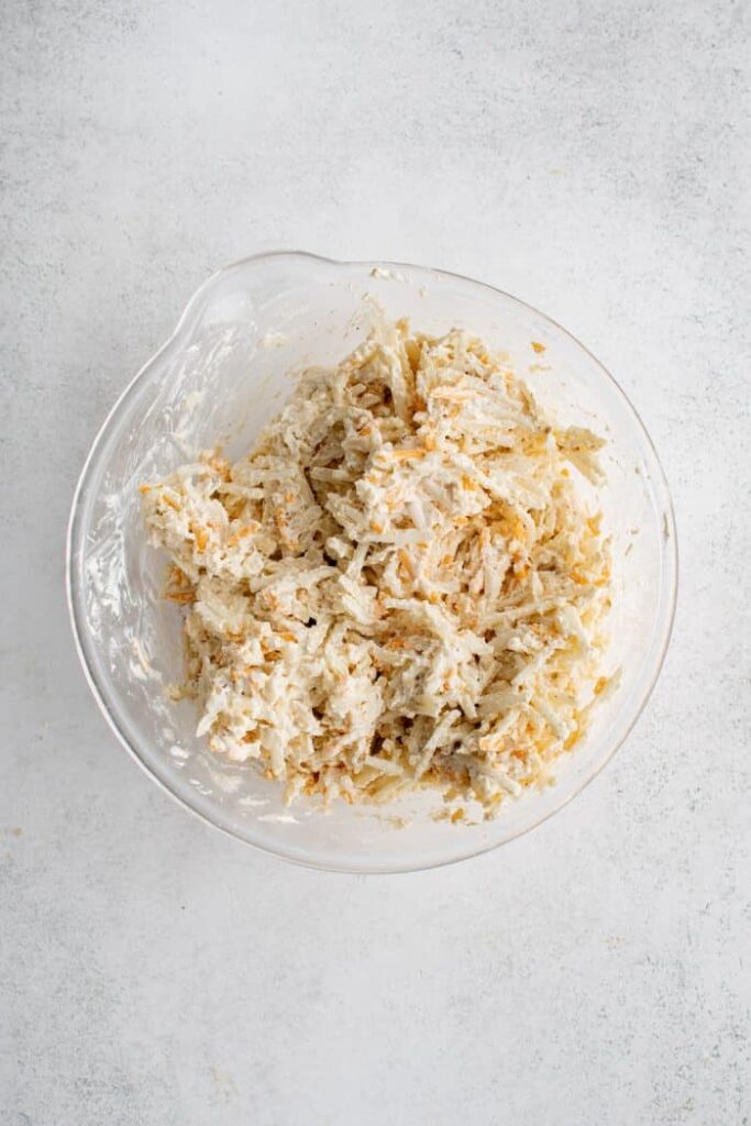 In a large bowl, stir together the shredded cheese, sour cream, cream of chicken soup, half of the melted butter, diced onion, garlic salt, onion powder, and black pepper until well combined 3