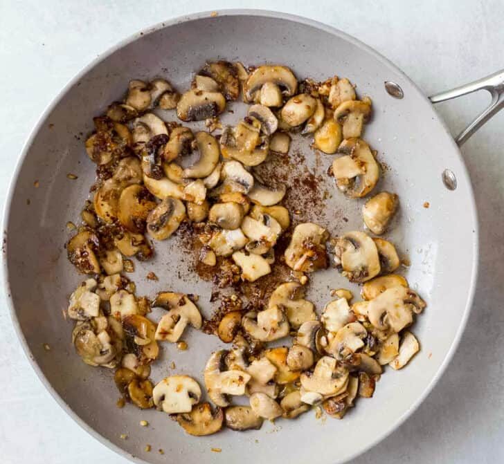 Add the sliced mushrooms and cook until they are browned and tender. Season lightly with salt and pepper to enhance flavor.