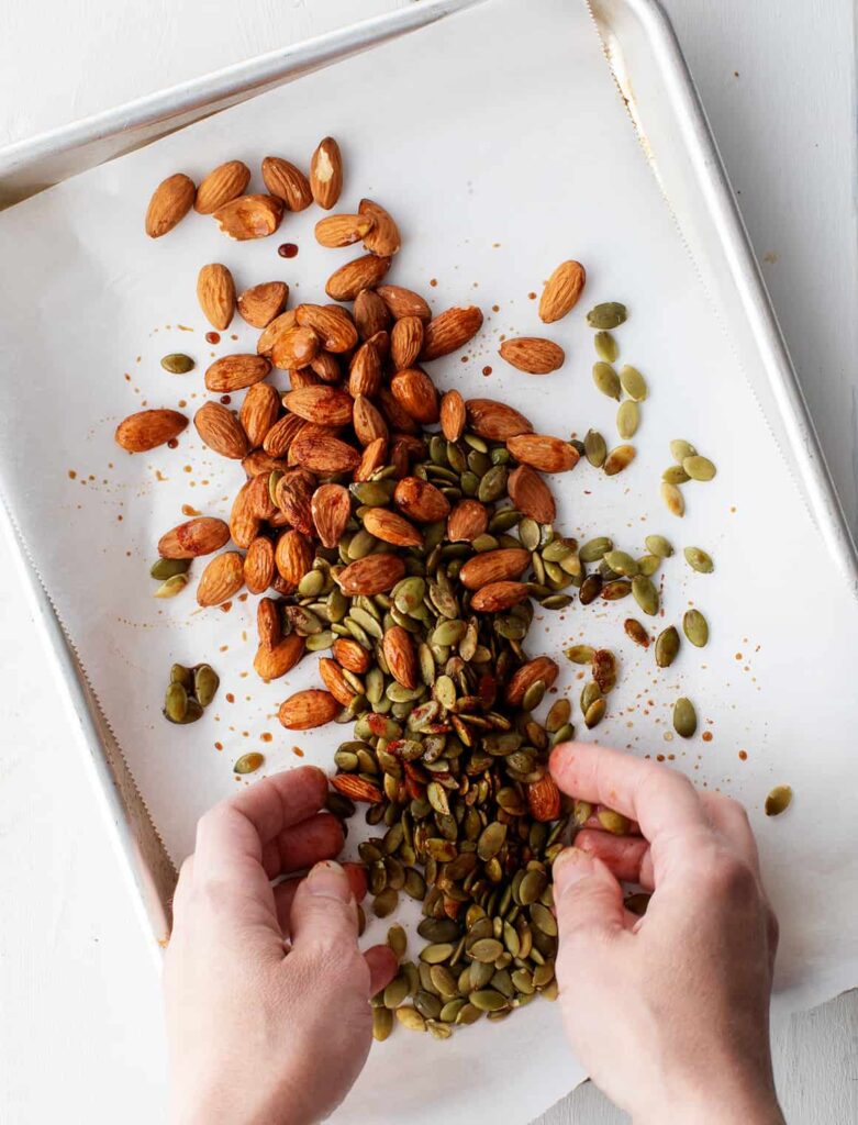 Spread the almonds and pepitas on the prepared baking sheet, then toss them with tamari, maple syrup, and smoked paprika until evenly coated