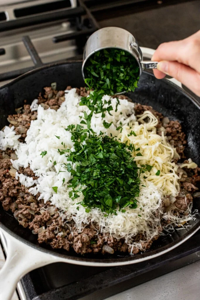 Turn off the heat and mix in marinara sauce, cooked rice, parsley, Parmesan, and part of the shredded cheese until everything is evenly combined